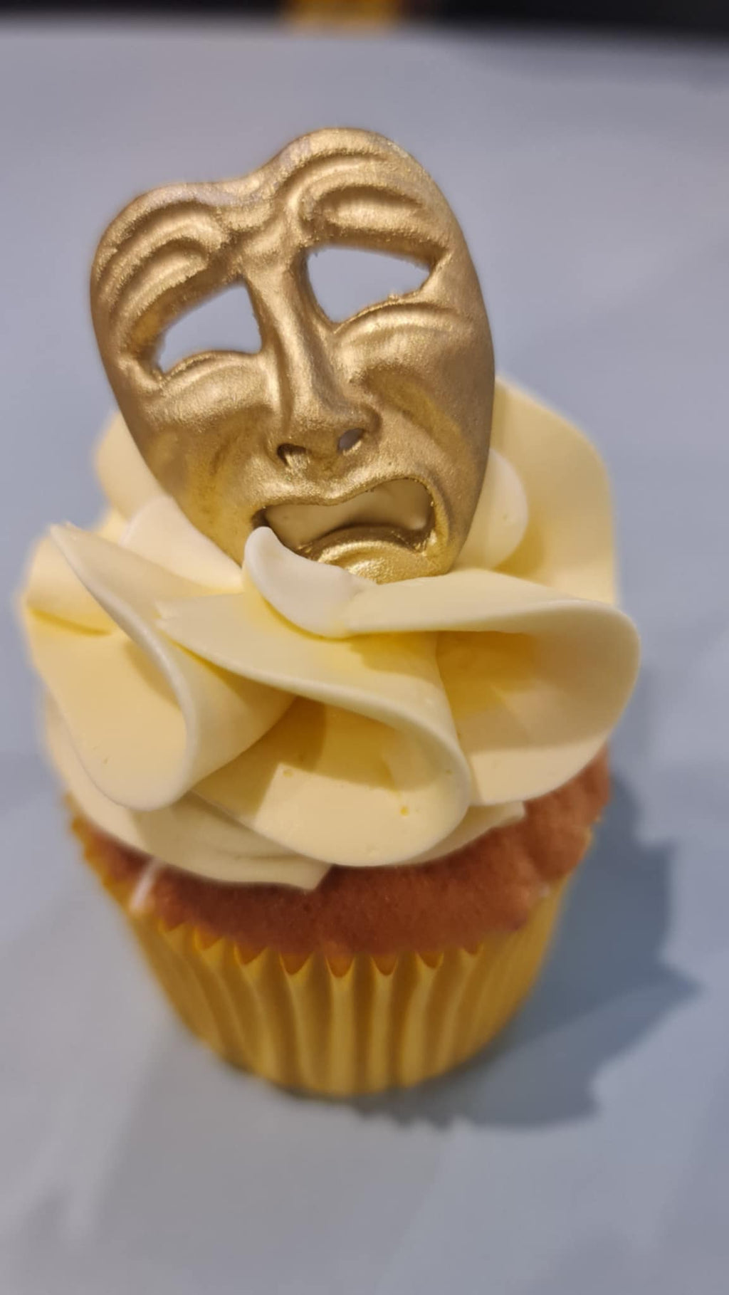 Cupcake with gold theater mask in yellow case