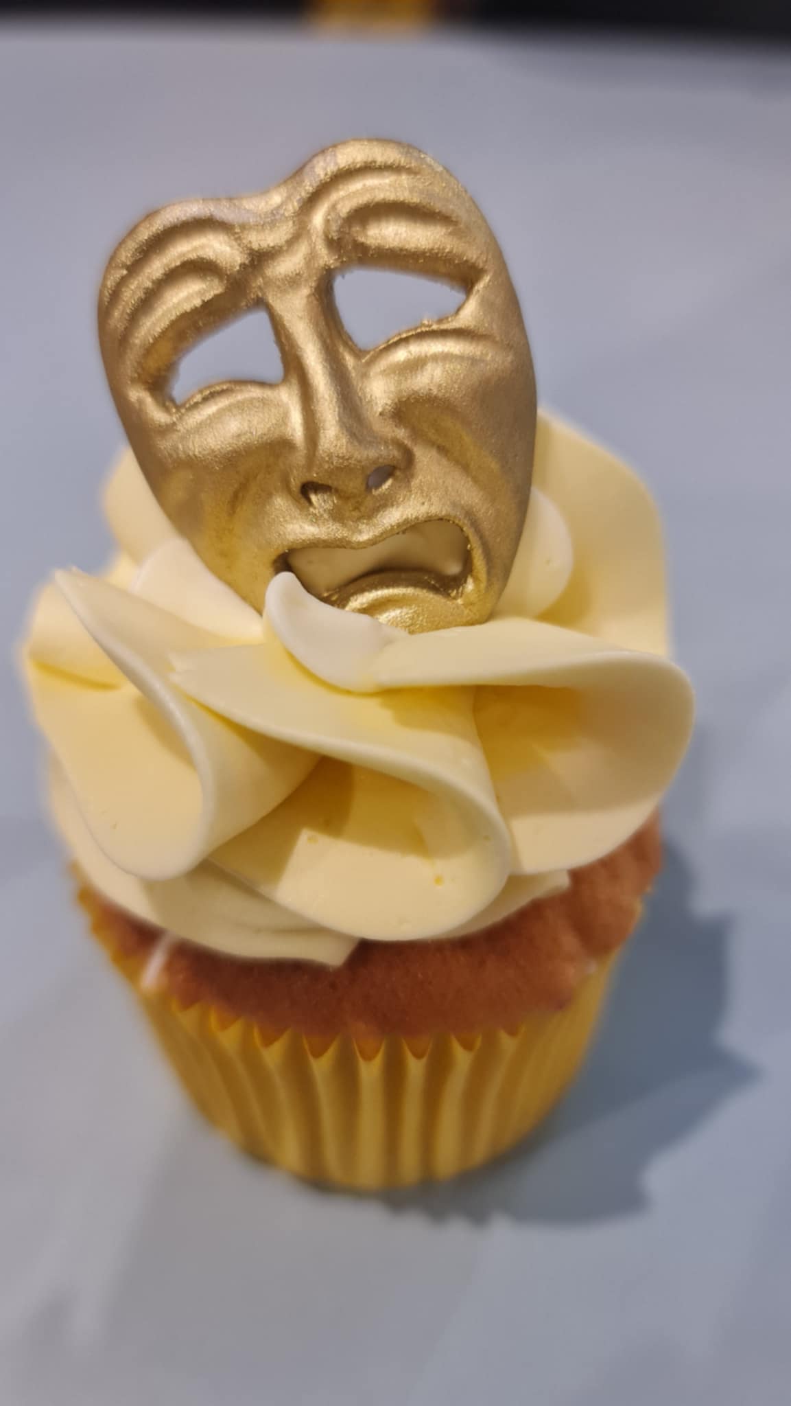 Cupcake with gold theater mask in yellow case